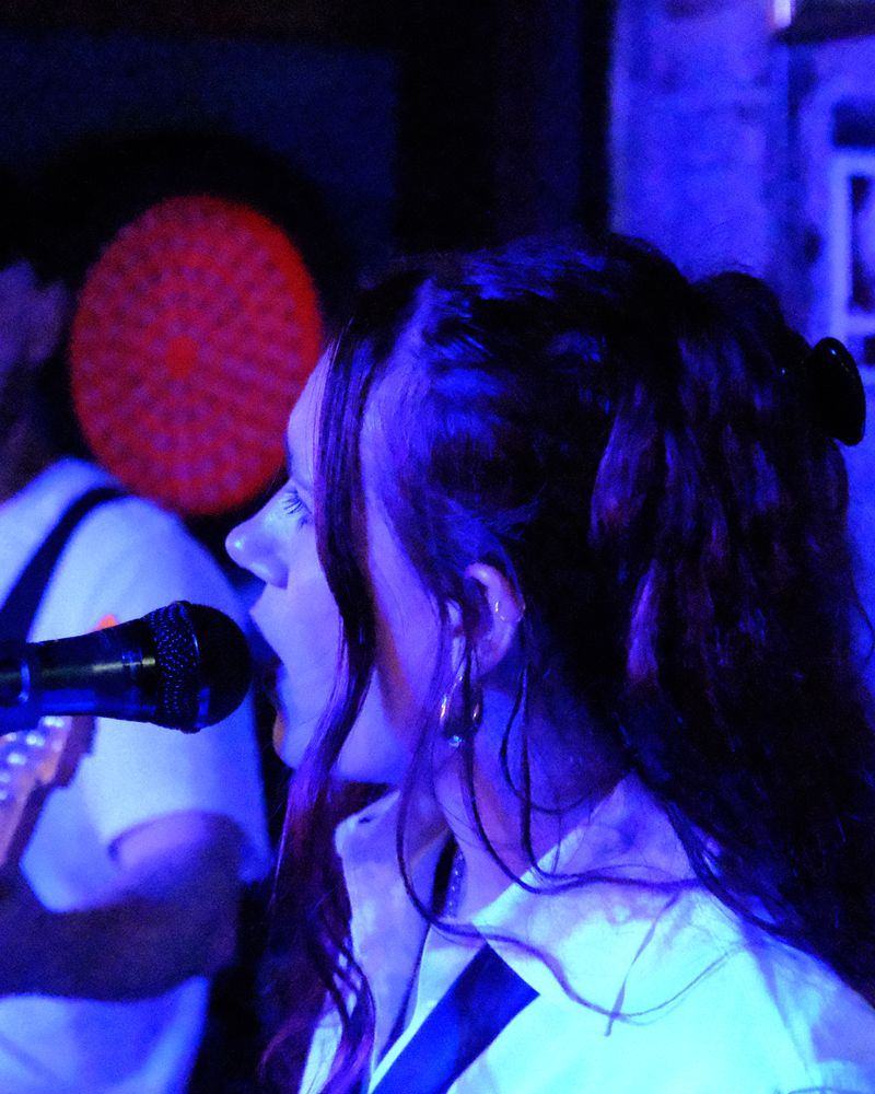 Close-up of mollywater singing, lit in blue